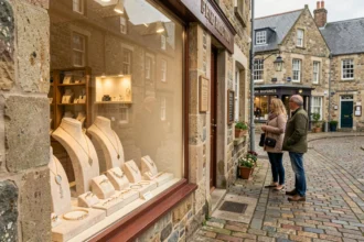 Vitrine d'une bijouterie bretonne sur une rue pavée avec architecture en pierre, présentant des bijoux sur des présentoirs en velours